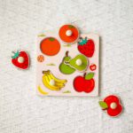 Montessori-geïnspireerde houten fruitpuzzel met vrolijke vormen zoals banaan, peer, appel, aardbei en sinaasappel, geschikt voor kinderen vanaf 0 jaar, met handige handvatten voor eenvoudige grip en plaatsing.